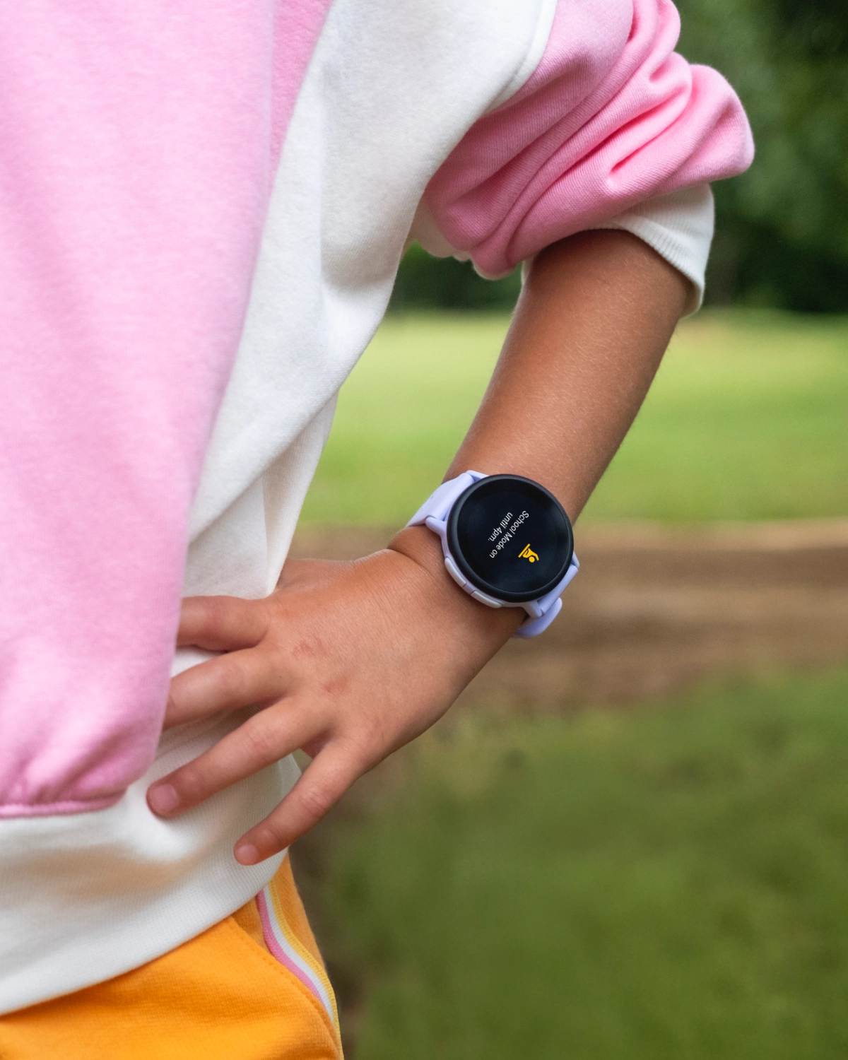 Zegarek Garmin Bounce widoczny na nadgarstku dziecka, które opiera rękę na biodrze.